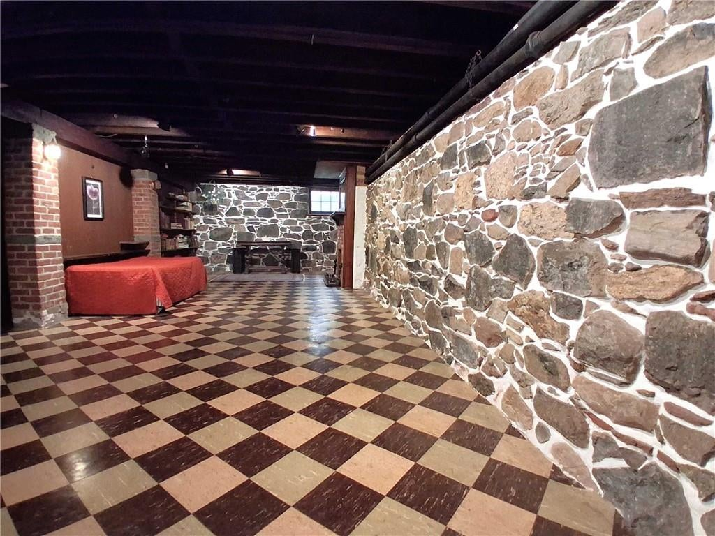 basement rumpus room with rubble stone walls and tile floor