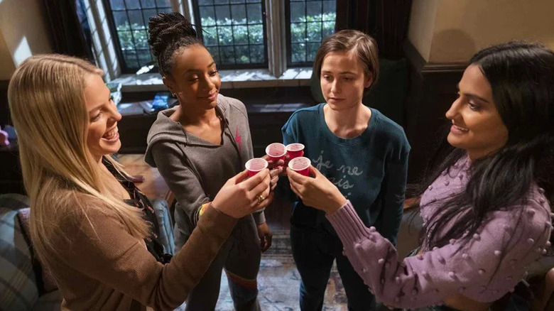 Reneé Rapp as Leighton, Alyah Chanelle Scott as Whitney, Pauline Chalamet as Kimberly, and Amrit Kaur as Bela cheersing with red shot glasses in The Sex Lives of College Girls