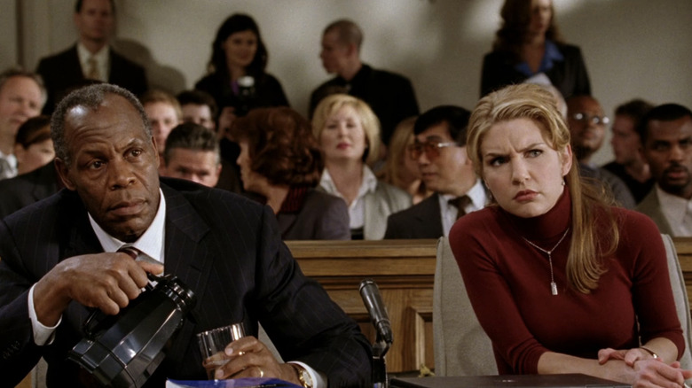 Danny Glover's Ken Hollister and Rhea Seehorn's Lori look confused as they sit side by side in court in The Shaggy Dog