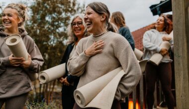 Women laughing together, holding yoga mats in hand outdoors