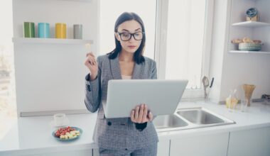 A person in a kitchen looks at a laptop.