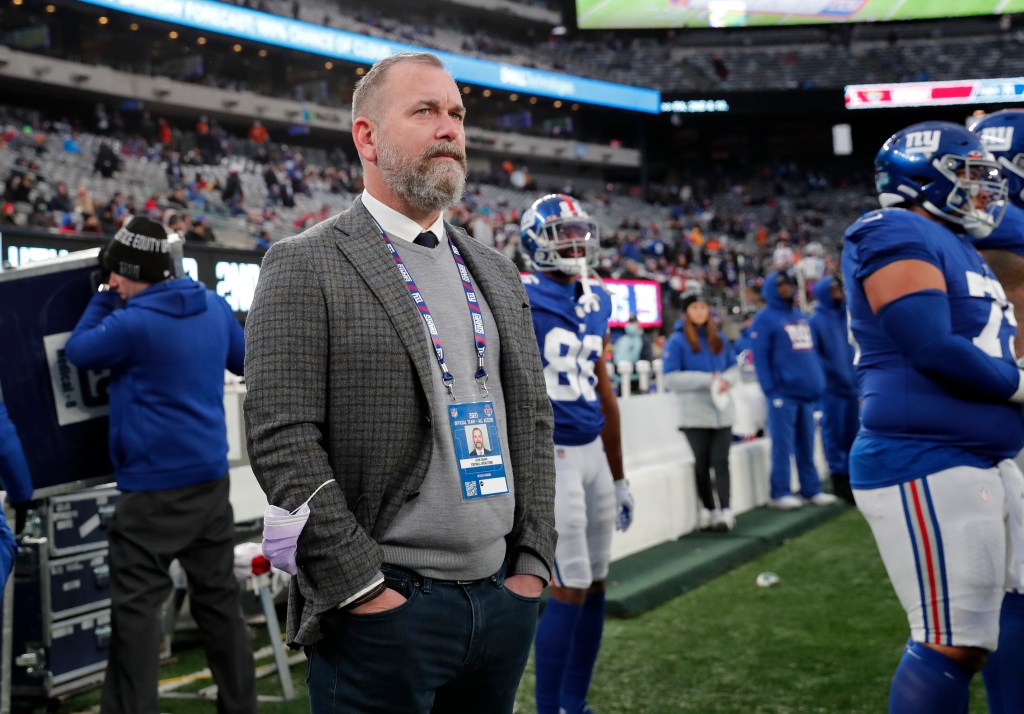 Kevin Abrams, New York Giants executive, wearing a grey jacket, sweater, and white collared shirt, stands on the sidelines of MetLife Stadium.