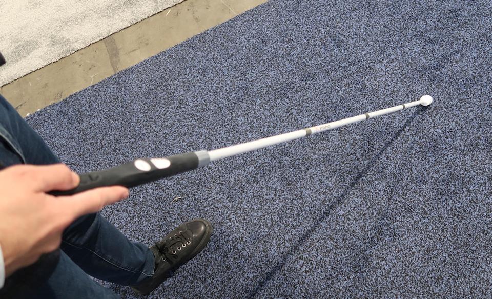 A person uses the Wewalk Smart Cane 2 to find their way through a CES booth. 