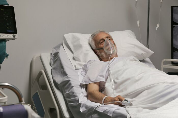Elderly patient in hospital bed with oxygen mask, representing patients leaving the hospital against medical advice.