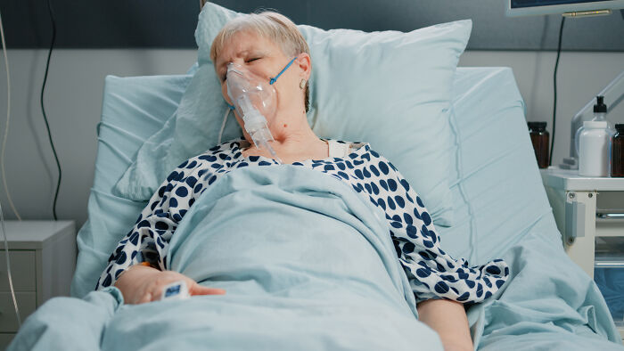 Elderly patient in hospital bed wearing oxygen mask, representing patients leaving hospital against medical advice.