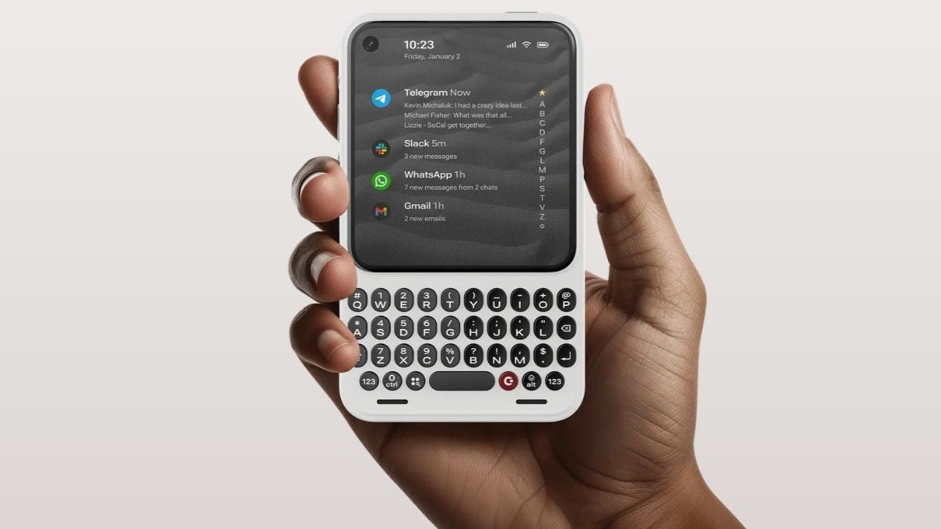 Clicks Communicator phone in a man's hand showing its screen and physical keyboard