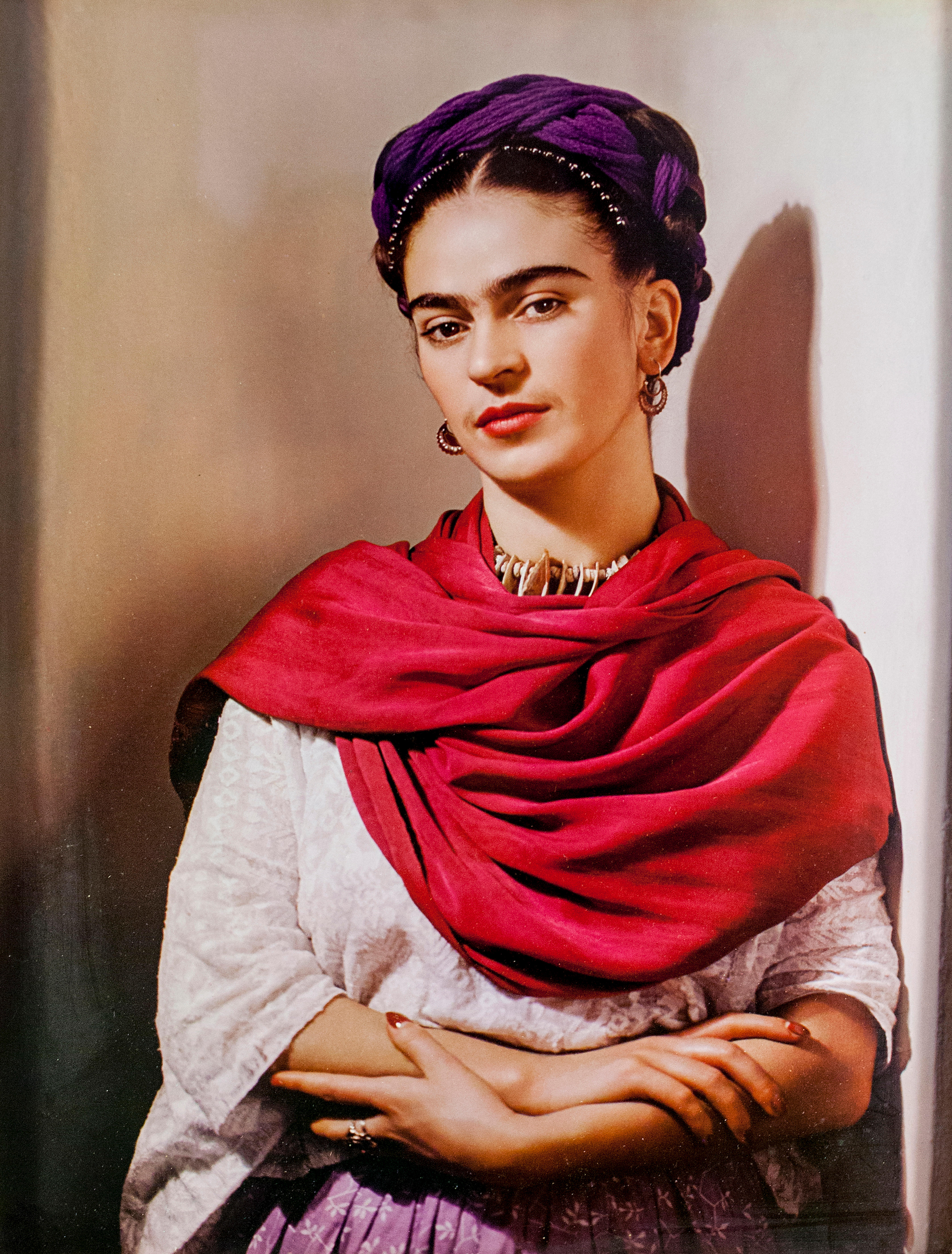 Portrait of Frida Kahlo in a purple headwrap and red shawl.