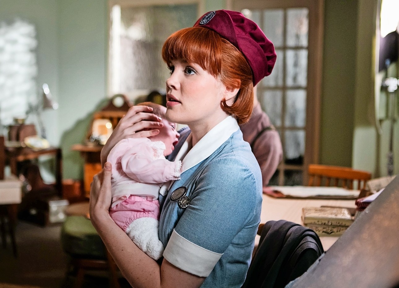 Nurse Patsy Mount, played by Emerald Fennell, holding a baby.