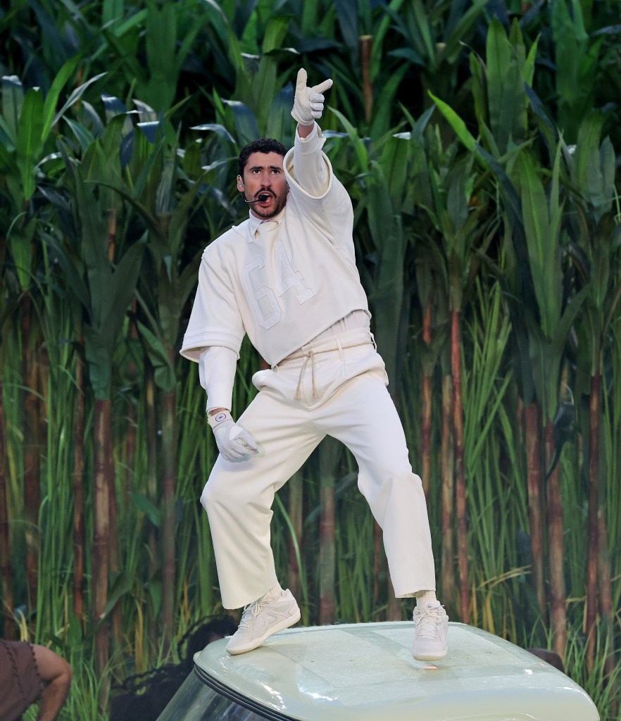 Bad Bunny performing during the Super Bowl halftime show, wearing a white outfit and pointing up.