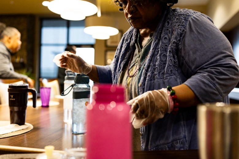 Green House resident Deborah Robinson puts waters on the table ahead of dinner for residents at the Thome Rivertown Senior Apartments in Detroit, Michigan, on Tuesday, Feb. 17, 2026. 