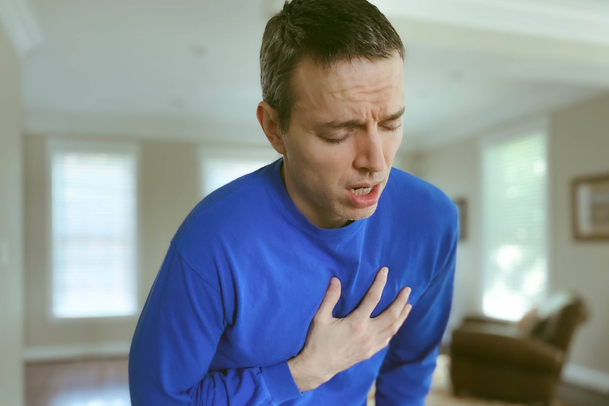 Close-up of mid adult man experiencing dyspnea (i.e., tightening in the chest, difficulty breathing, shortness of breath)