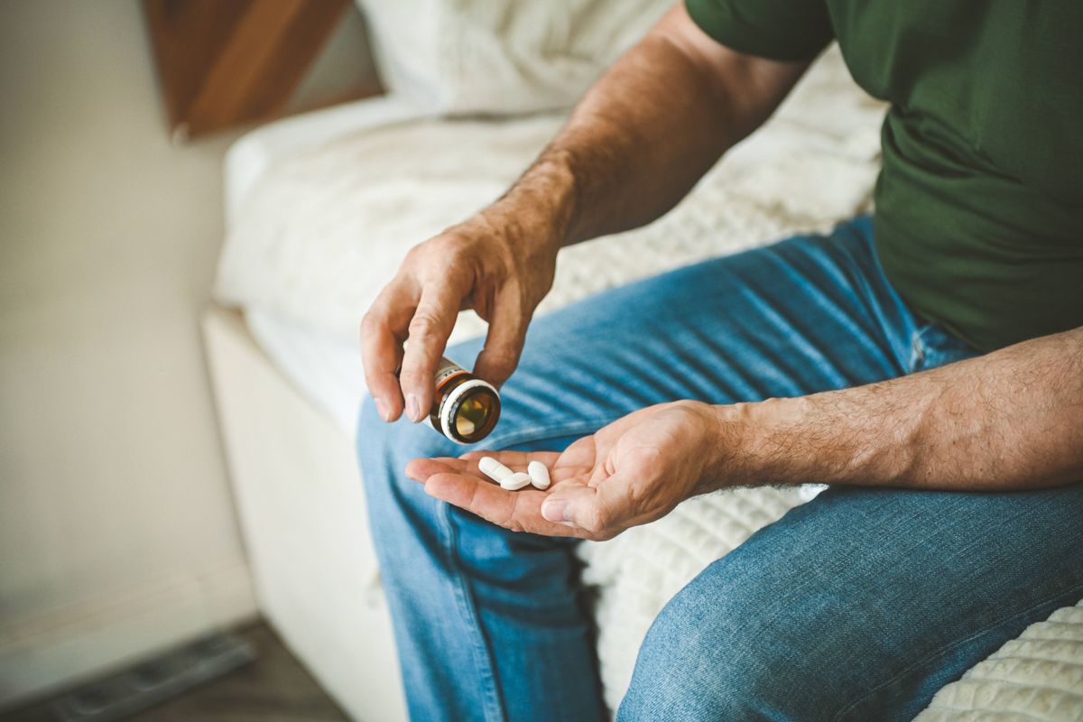 Mature adult man in cozy interior of bedroom ( taking medication)