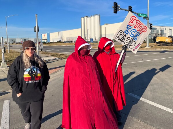 Melissa Kane, a self-described worried mother, joins protestors clad in red cloaks inspired by the dystopian novel and TV series, "The Handmaid's Tale," as they protest outside a warehouse federal officials are touring to consider repurposing for an ICE detention facility, in Kansas City, Mo., Thursday, Jan. 15, 2026. (AP Photo/Heather Hollingsworth)