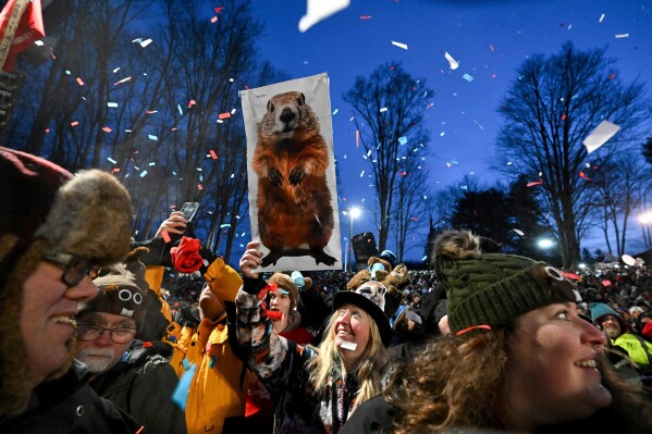 People take part in the festivities while waiting for Punxsutawney Phil, the weather prognosticating groundhog, to come out and make his prediction during the 139th celebration of Groundhog Day on Gobbler's Knob in Punxsutawney, Pa., Feb. 2, 2025. (AP Photo/Barry Reeger, File)