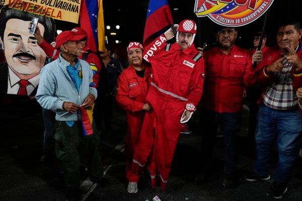 A PDVSA worker of the state-owned oil company carries a cutout of former President Nicolas Maduro dressed as an oil worker during a rally to back an oil reform bill proposed by acting President Delcy Rodriguez to loosen state control and open the industry to private and foreign investment in Caracas, Venezuela, Jan. 29, 2026. (AP Photo/Ariana Cubillos, File)