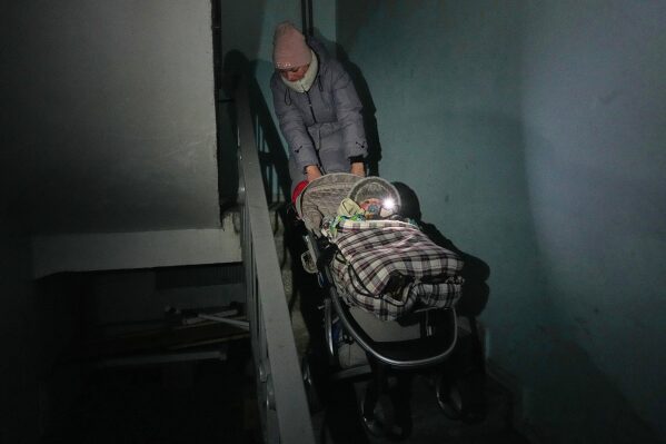 Yuliia Dolotova pulls her son in a stroller up apartment stairs during a power outage caused by Russia's repeated air strikes on the country's power grid, in Kyiv, Ukraine, Feb. 2, 2026. (AP Photo/Sergey Grits, File)