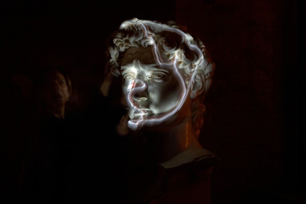 Stefania Terre, who is blind, uses a small light on her fingers while touching a life-size reproduction of the head of Michelangelo's David as she poses for a long-exposure photograph at the Omero Tactile Museum in Ancona, Italy, Jan. 15, 2026. (AP Photo/Alessandra Tarantino, File)