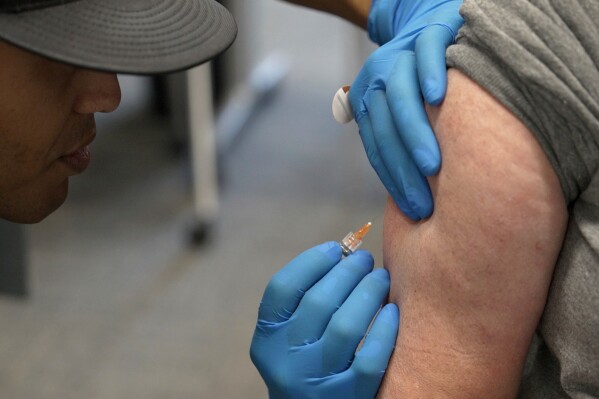 FILE - Matt Caldwell, left, a Lubbock Fire Department official, administers a measles, mumps and rubella vaccine to Clair May at the Lubbock Health Department, Feb. 26, 2025, in Lubbock, Texas. (AP Photo/Mary Conlon, File)