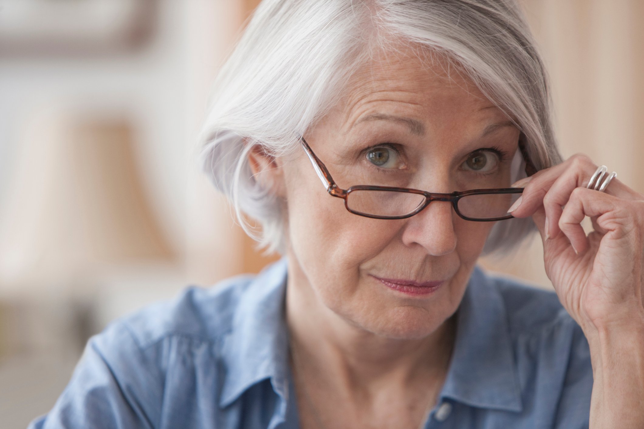 A person holding eyeglasses on the bridge of the nose.