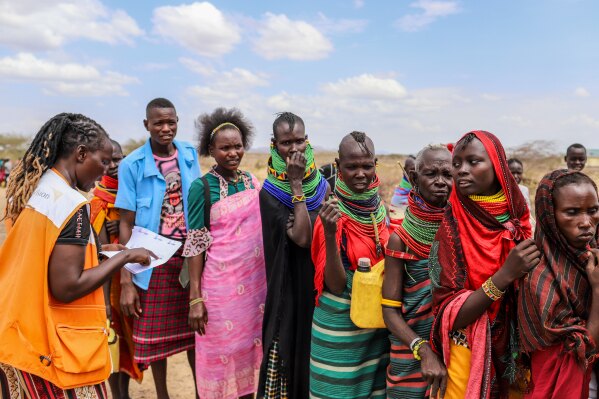 World Vision Kenya humanitarian worker verifies food assistance details as people queue for aid as prolonged drought continues in Nalemkais Village, Turkana County, Kenya, Sunday, Feb. 8, 2026. (AP Photo/Patrick Ngugi)