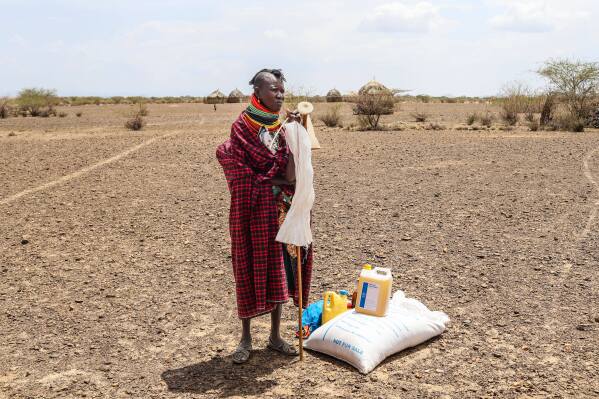A woman stands beside her food ration after distribution of aid, in Nalemkais Village, Turkana County, Kenya, Sunday, Feb. 8, 2026. (AP Photo/Patrick Ngugi)