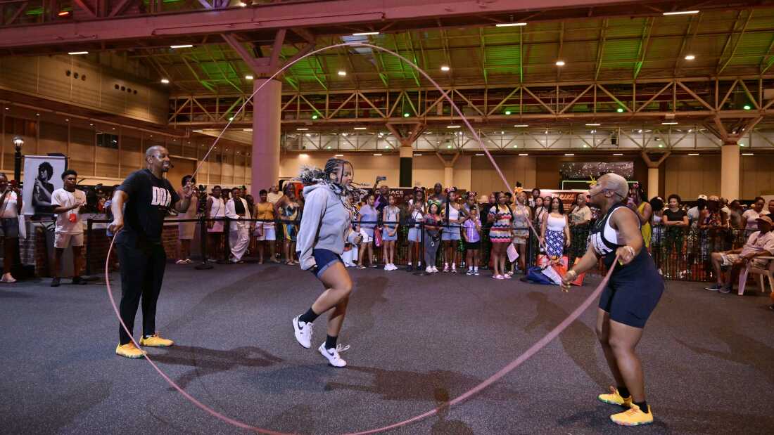 Guests Double Dutch at the 2025 ESSENCE Festival of Culture presented by Coca-Cola at Ernest N. Morial Convention Center on July 5, 2025 in New Orleans. Many people stand around watching as a girl double-dutchs.