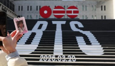 A visitor takes a picture of a photocard in front of a street installation promoting K-pop boy band BTS
