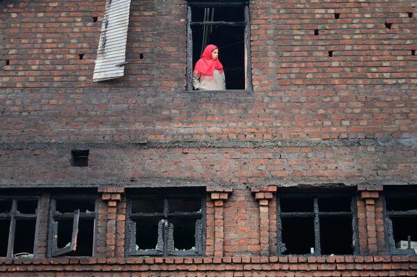 A Kashmiri woman looks out from a house damaged in an overnight fire in Srinagar, Indian controlled Kashmir, Feb. 11, 2026. (AP Photo/Mukhtar Khan, File)