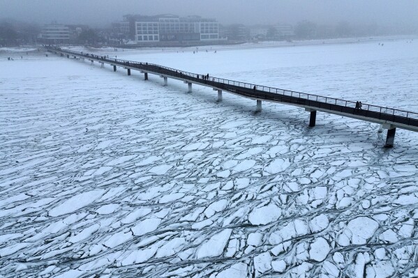 People walk on the pier over the frozen Baltic Sea in Scharbeutz, northern Germany, Feb. 7, 2026. (AP Photo/Michael Probst, File)