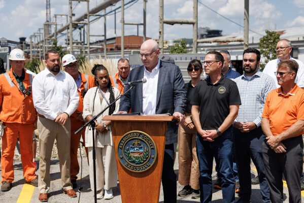 U.S. Steel President and Chief Executive Officer David B. Burritt, accompanied by Pennsylvania Gov. Josh Shapiro, center right, and other officials, speaks during a news conference at U.S. Steel's Clairton Coke Works in Clairton, Pa., on Tuesday, Aug. 12, 2025, a day after an explosion at the facility killed two workers. (Quinn Glabicki/Pittsburgh's Public Source via AP)