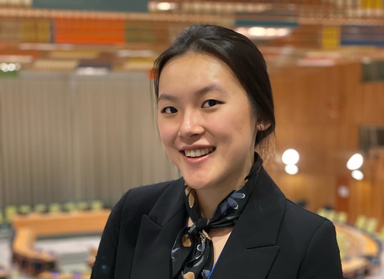 A smiling woman wearing a blazer and a colourful neck scarf. 