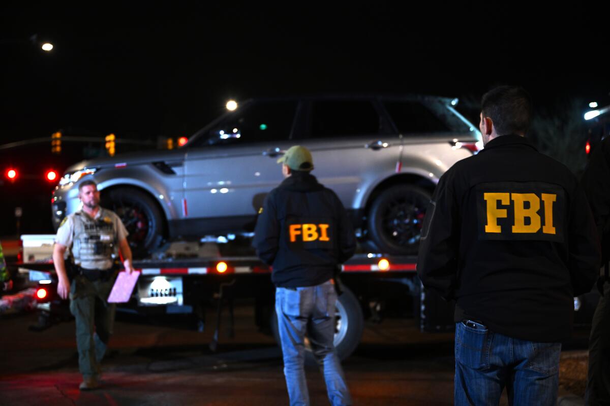 FBI agents watch as a vehicle is towed