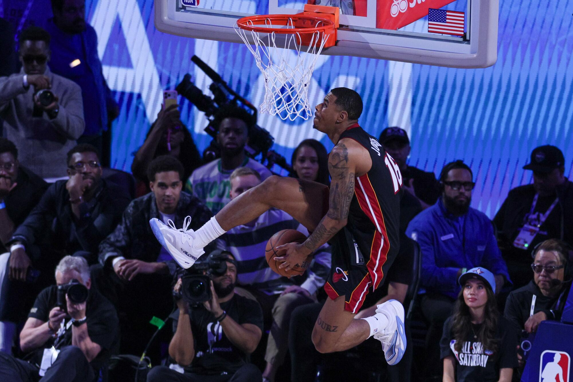 Slam dunk winner Keshad Johnson elevates toward the rim while passing the ball from hand to hand under his leg.
