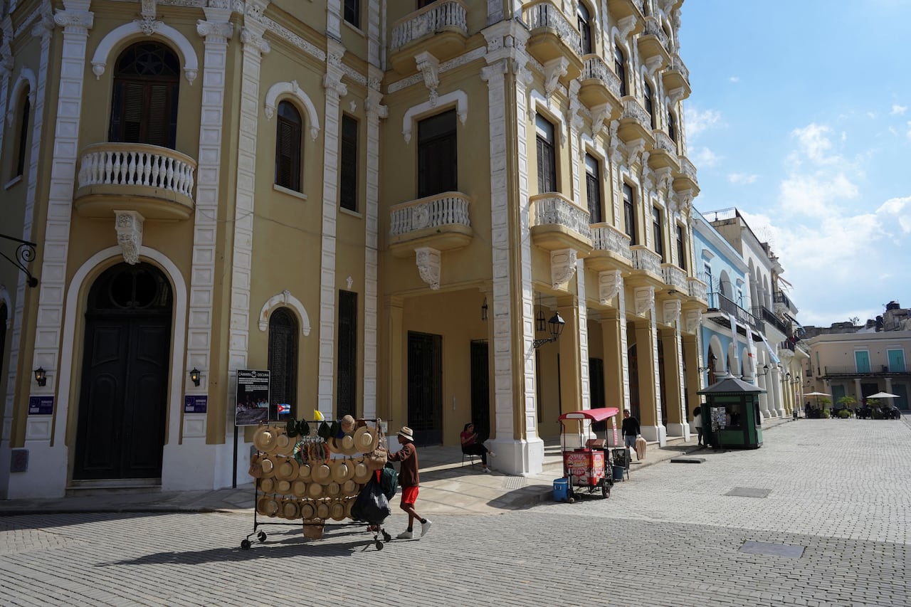 A person selling hats pushes a cart through a mostly empty plaza.
