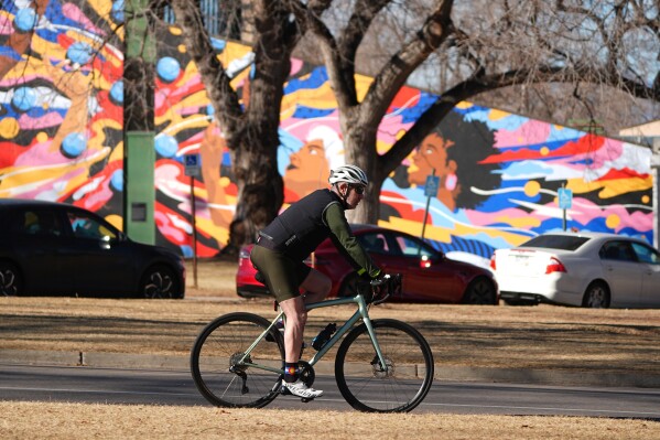 Taking advantage of daytime hgh temperatures in the 60s, a cyclist wheels through Washington Park, Friday, Feb. 6, 2026, in Denver. (AP Photo/David Zalubowski)