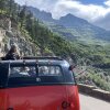 Along Glacier National Park's Going to the Sun Road, tourists admire the view from one of the park’s vintage red buses