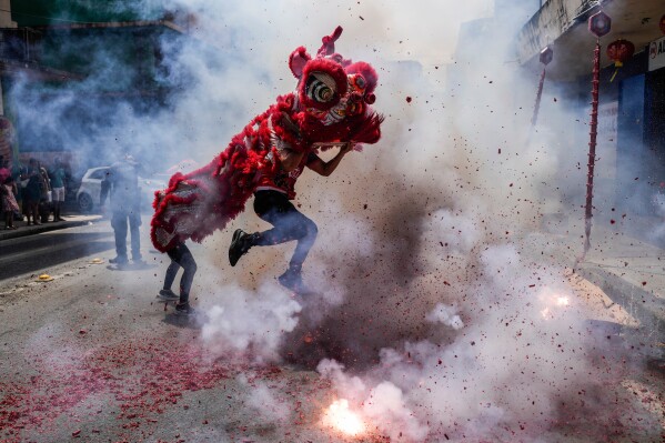 People perform a lion dance as fireworks explode during Lunar New Year celebrations in Panama City, Feb. 18, 2026. (AP Photo/Matias Delacroix, File)