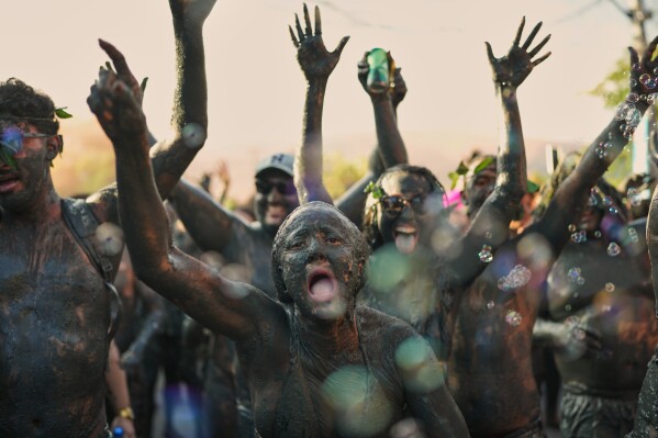 Revelers cheer during the Mud Block carnival party in Paraty, Brazil, Feb. 14, 2026. (AP Photo/Andre Penner, File)