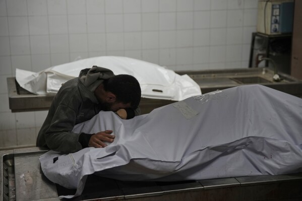 Magdi Abu Al-Khair bids farewell to his mother Amal Abu Al-Khair at Al-Shifa Hospital in Gaza City, Friday, Jan. 2, 2026, after she and her grandchild Saud were killed when their tent caught fire overnight at the Yarmouk displacement camp. (AP Photo/Jehad Alshrafi)