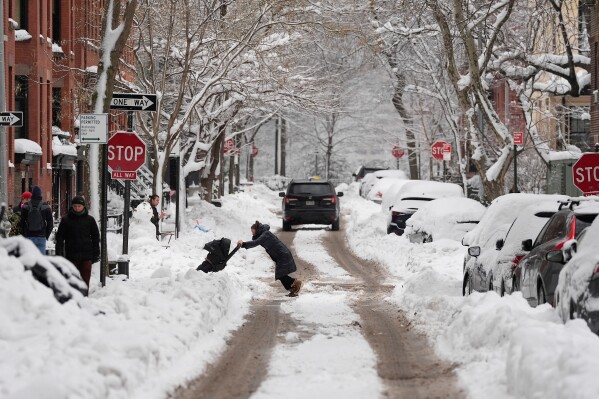 A woman pushes a stroller through plowed snow, Wednesday, Feb. 25, 2026, in the Brooklyn borough of New York. (AP Photo/Yuki Iwamura)