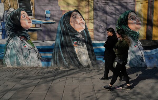 Women walk past a mural at a girls school at Enqelab-e-Eslami, or Islamic Revolution Street in downtown Tehran, Iran, Wednesday, Feb. 25, 2026. (AP Photo/Vahid Salemi)