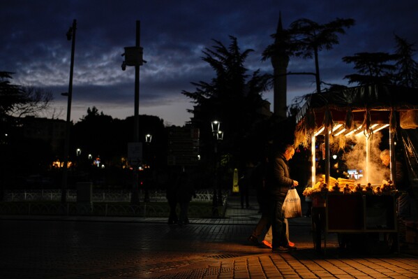 A street vendor sells corn to a customer after sunset in Istanbul, Turkey, Wednesday, Feb. 25, 2026. (AP Photo/Emrah Gurel)