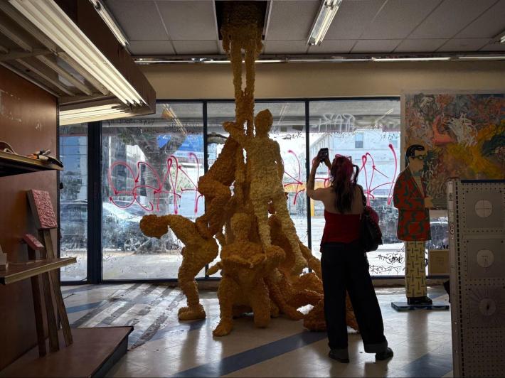 a sculpture of bodies supporting one person standing and entering the ceiling above
