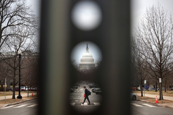 A pedestrian walks along Columbus Circle NE near the U.S. Capitol, Thursday, Feb. 26, 2026, in Washington. (AP Photo/Tom Brenner)