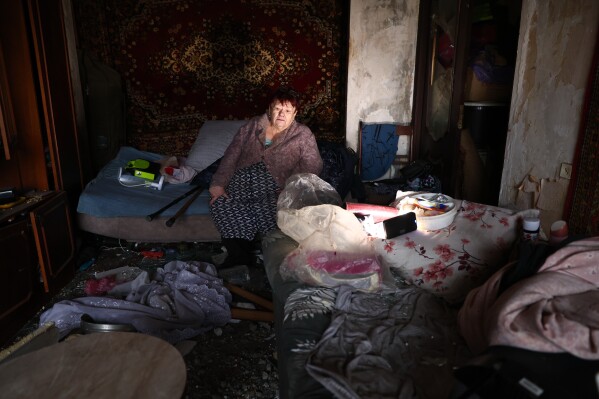 An elderly woman sits in her damaged apartment after a Russian drone hit an apartment building in Zaporizhzhia, Ukraine, Thursday, Feb. 26, 2026. (AP Photo/Kateryna Klochko)