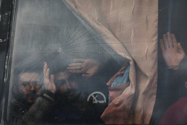 Syrian government prisoners wave from a bus after their release in a prisoner exchange between Syrian government forces and Druze militiamen in Sweida province, Syria, Thursday, Feb. 26, 2026. (AP Photo/Ghaith Alsayed)