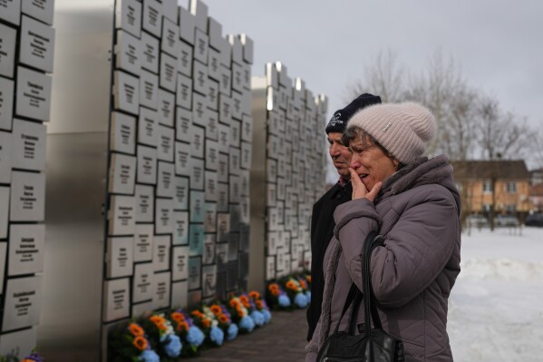 Relatives of people killed during the Russian occupation visit the Wall of Remembrance during a ceremony to mark the fourth anniversary of the Russian invasion of Ukraine, in Bucha, Ukraine, Feb. 24, 2026. (AP Photo/Sergei Grits, File)