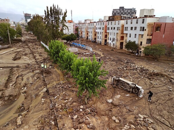 A man takes photos of a destroyed road after heavy rain triggered flooding in Arequipa, Peru, Feb. 23, 2026. (AP Photo/Jose Sotomayor, File)