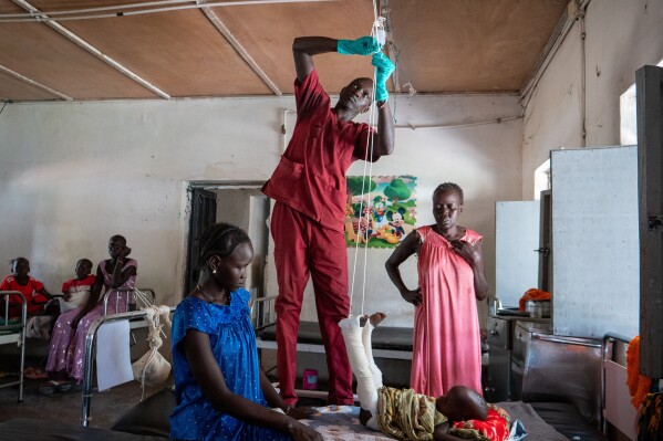 Nyayual Chuol, right, watches her 18-month-old grandson Kool Gatyen Pajock, who was shot during conflict, receive treatment at the Akobo County Hospital in South Sudan, Feb. 21, 2026. (AP Photo/Florence Miettaux, File)