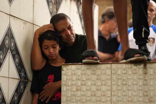 Friends of 11-year-old Bernardo Lopes, who died during heavy rains and flooding, attend his burial in Juiz de Fora, Minas Gerais state, Brazil, Feb. 25, 2026. (AP Photo/Silvia Izquierdo, File)